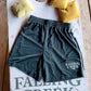 Green Athletic Training Shorts with White Stripe and Falling Creek Camp Logo on Left Leg. Pictured on a cornhole board.